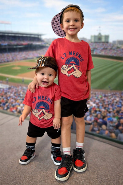 Two children wearing red t-shirts that say L-7 Weenie inspired by Sandlot at a stadium.