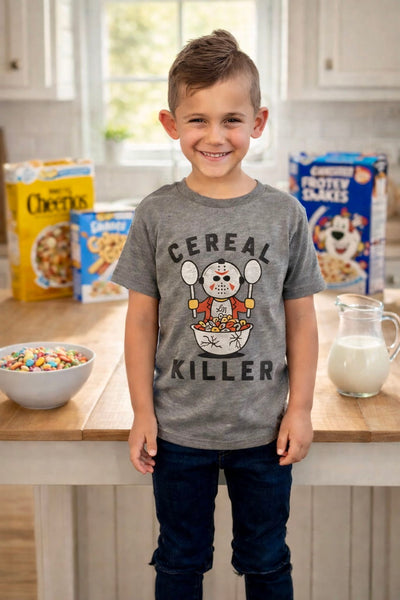 Child wearing a 'Cereal Killer' shirt in a kitchen with cereal boxes and milk.