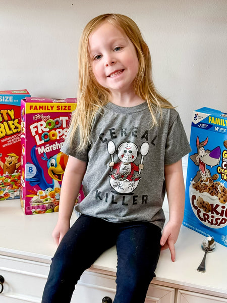 Child wearing a 'Cereal Killer' t-shirt in front of cereal boxes